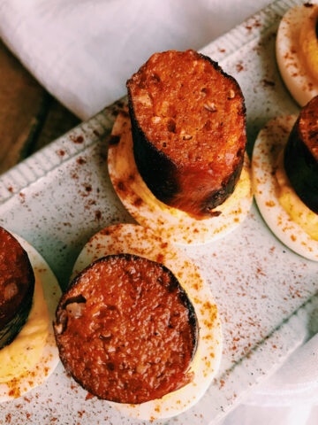closeup of deviled eggs with chorizo links on top