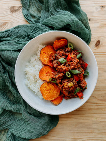 A Sloppy Joe Bowl in a white dish on a green piece of fabric over a wooden surface