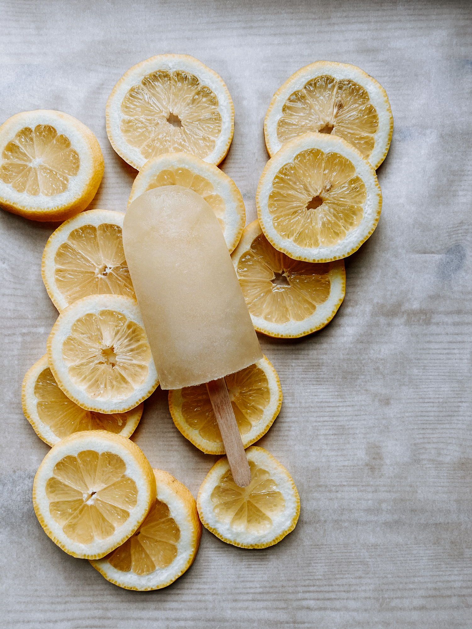 a parchment paper lined tray with lemon slices and a single harry potter inspired lemon ice pop resting on top of the lemons