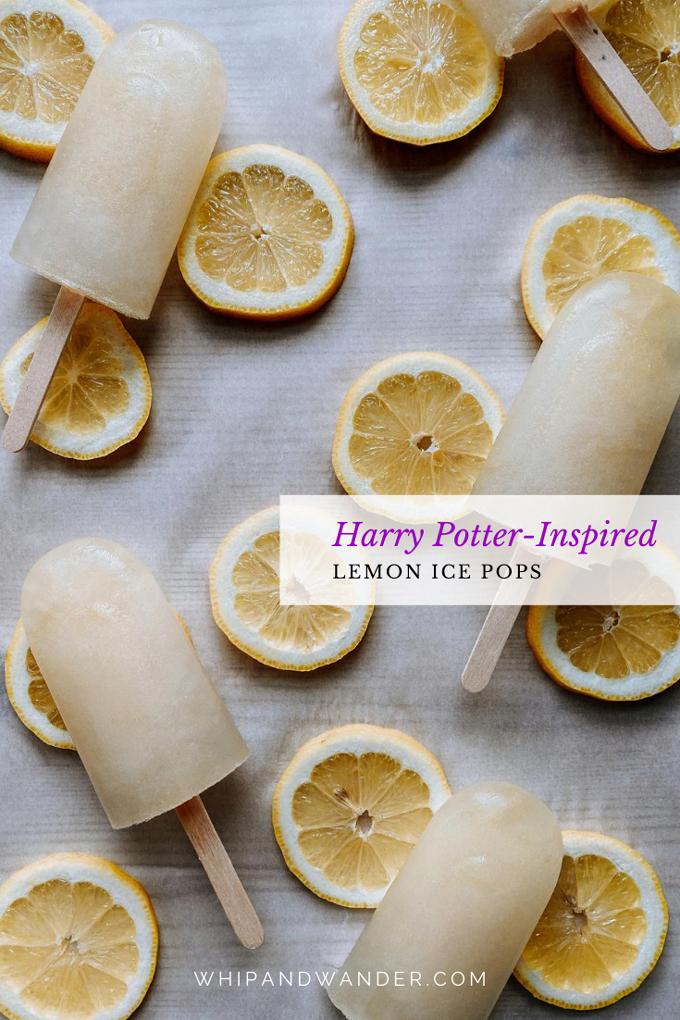 lemon popsicles resting on top of lemon slices on a parchment paper lined surface
