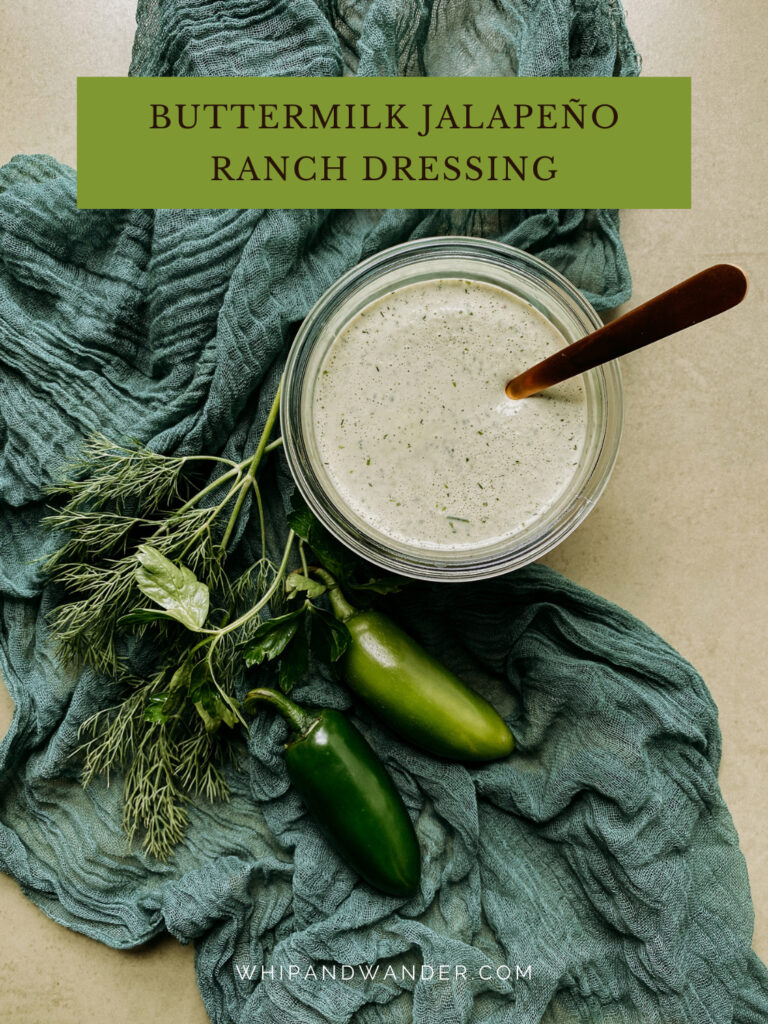 a gold spoon resting in a container of Buttermilk Jalapeno Ranch Dressing on a green cloth