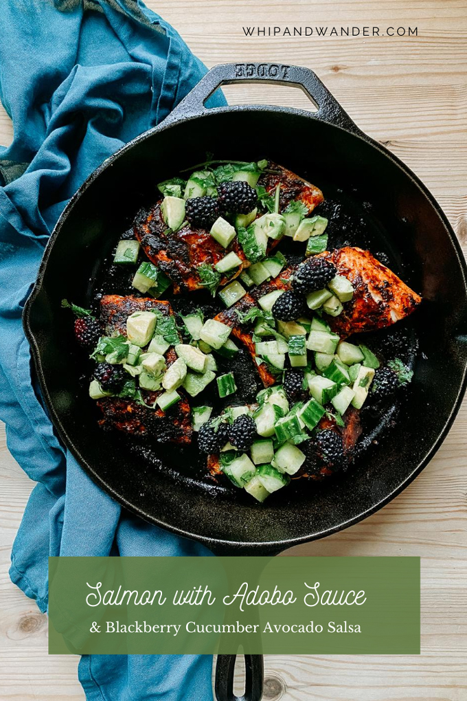 a wooden surface with a cast iron pan with seared salmon with adobo sauce and green salsa resting on a blue towel