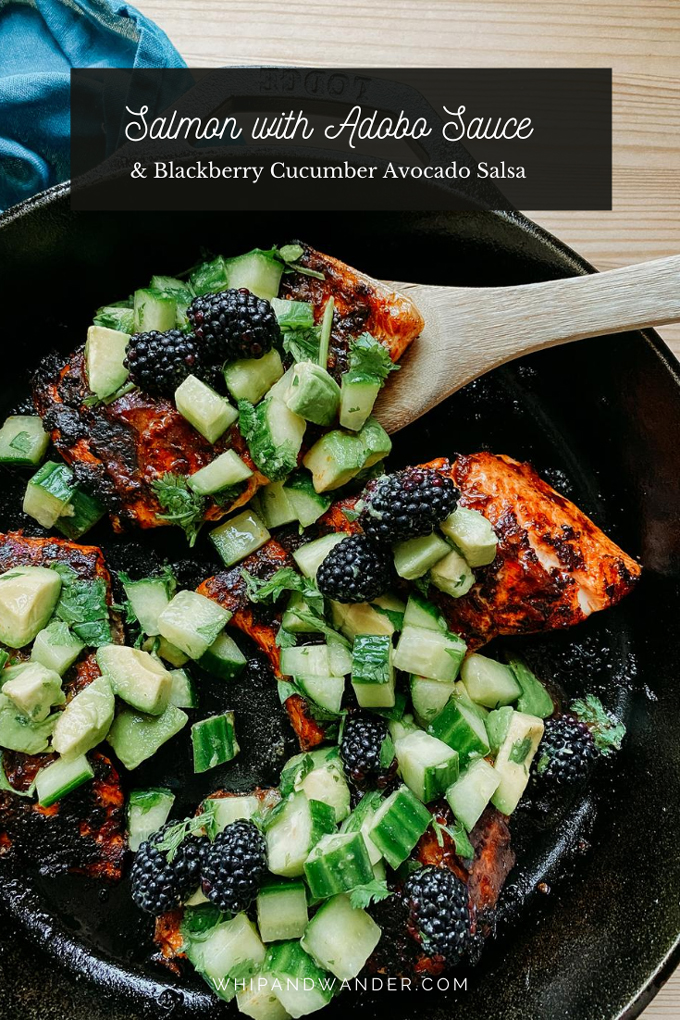 a wooden serving spoon dishing a piece of salmon covered in adobo sauce, avocado, cucumber, and blackberries out of a black pan