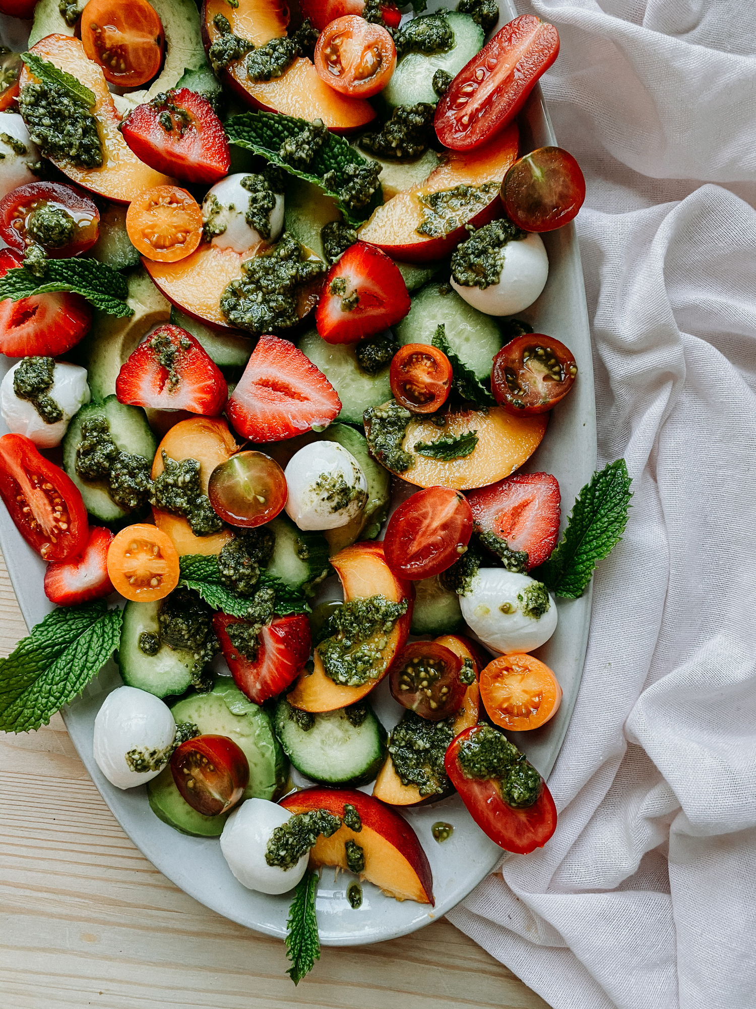 strawberry peach salad on a white platter resting on a white towel