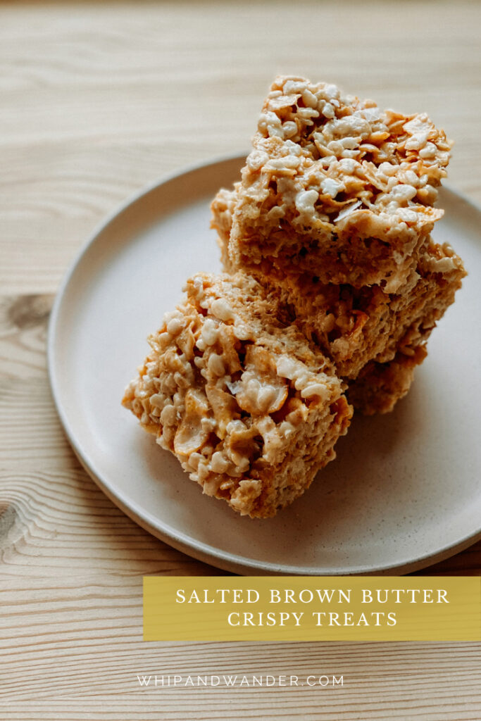 Salted Brown Butter Crispy Treats stacked on a light pink stoneware plate on a wooden surface