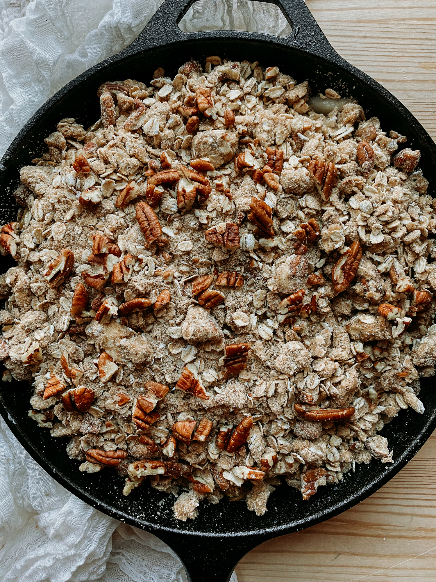 a cast iron pan which has an unbaked pear crisp conained in it