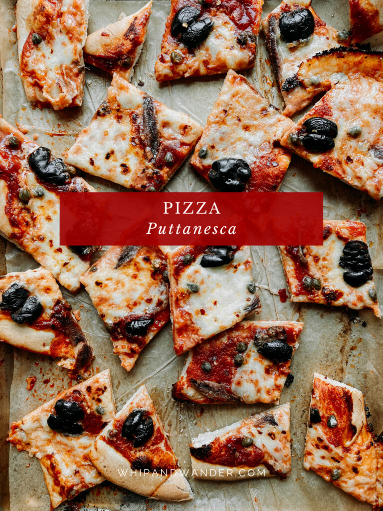 pieces of pizza topped with anchovies, mozzarella, and olives resting on a baking sheet