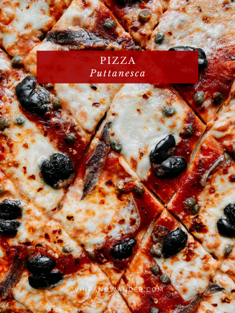 a pizza topped with capers, olives, anchovies, and mozzarella that has beens sliced into diamond shapes