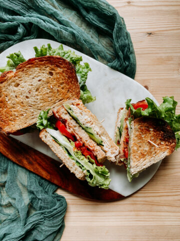 crab club sandwiches resting on a marble board on a wooden surface