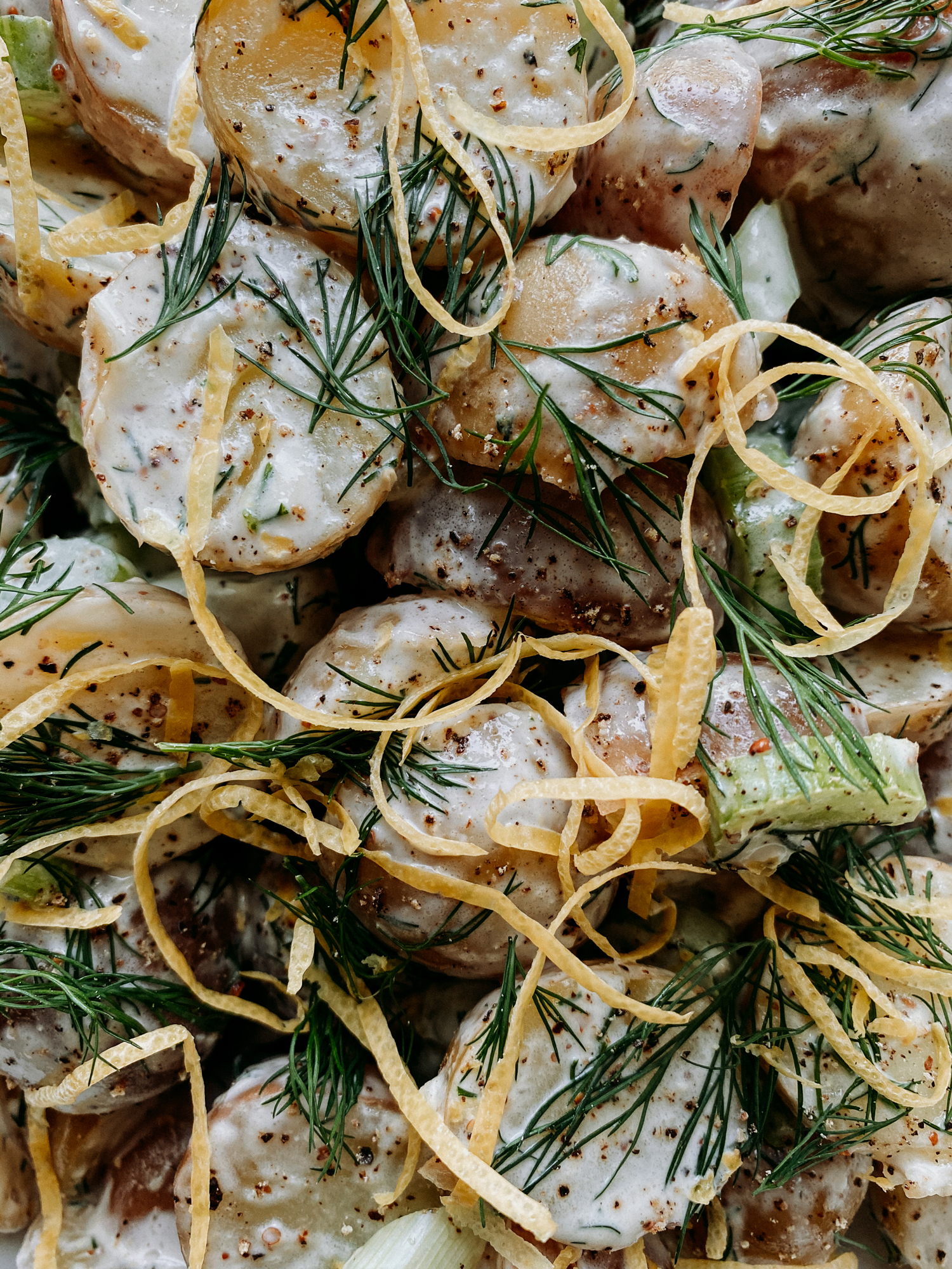 closeup of Creamy Dijon Dill Potato Salad with lemon zest curls on top