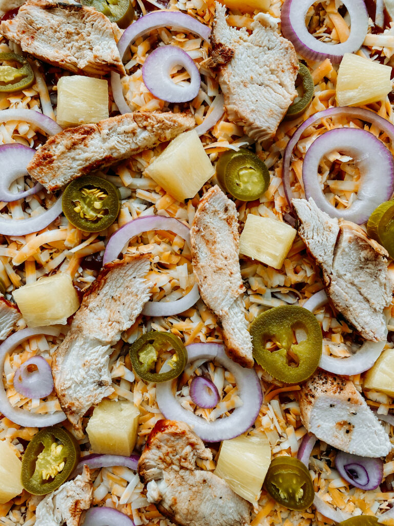 a closeup of the ingredients on an unbaked BBQ Chicken Pizza