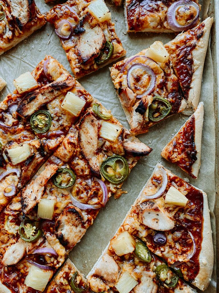 square slices of pizza with BBQ Chicken, pineapple, jalapenos, and red onion