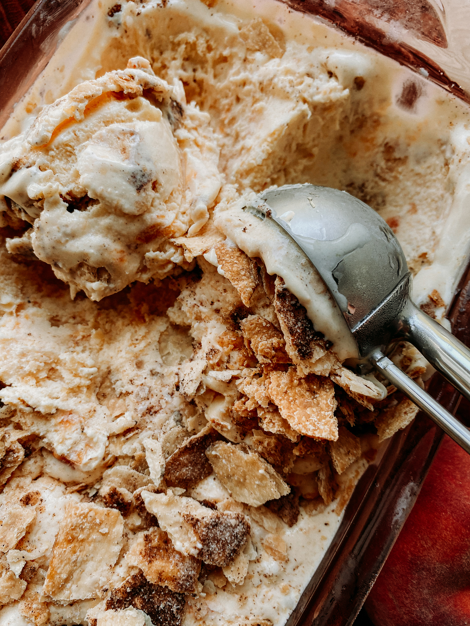 a metal ice cream scoop pushing through peach pie ice cream
