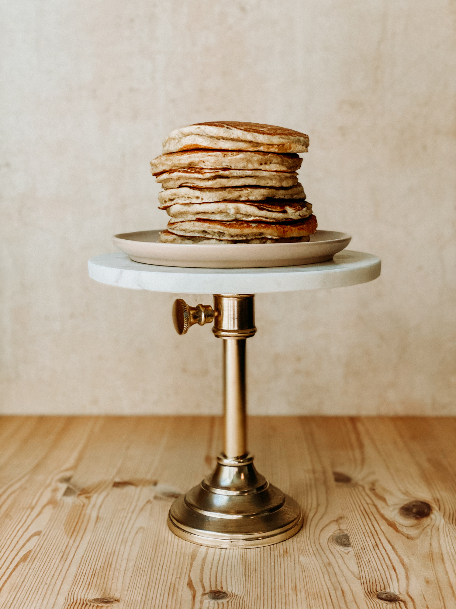 a stack of sourdough discard pancakes sacked on a plate on top of a cake stand