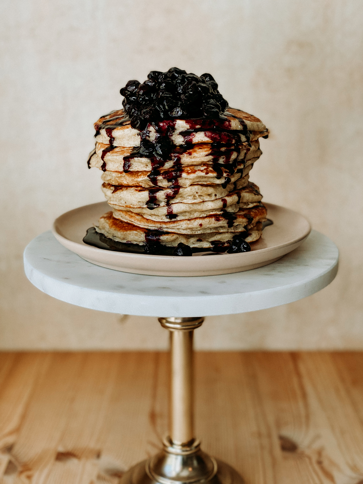 stacks of sourdough discard pancakes with blueberry sauce on a pink plate on a white topped stand