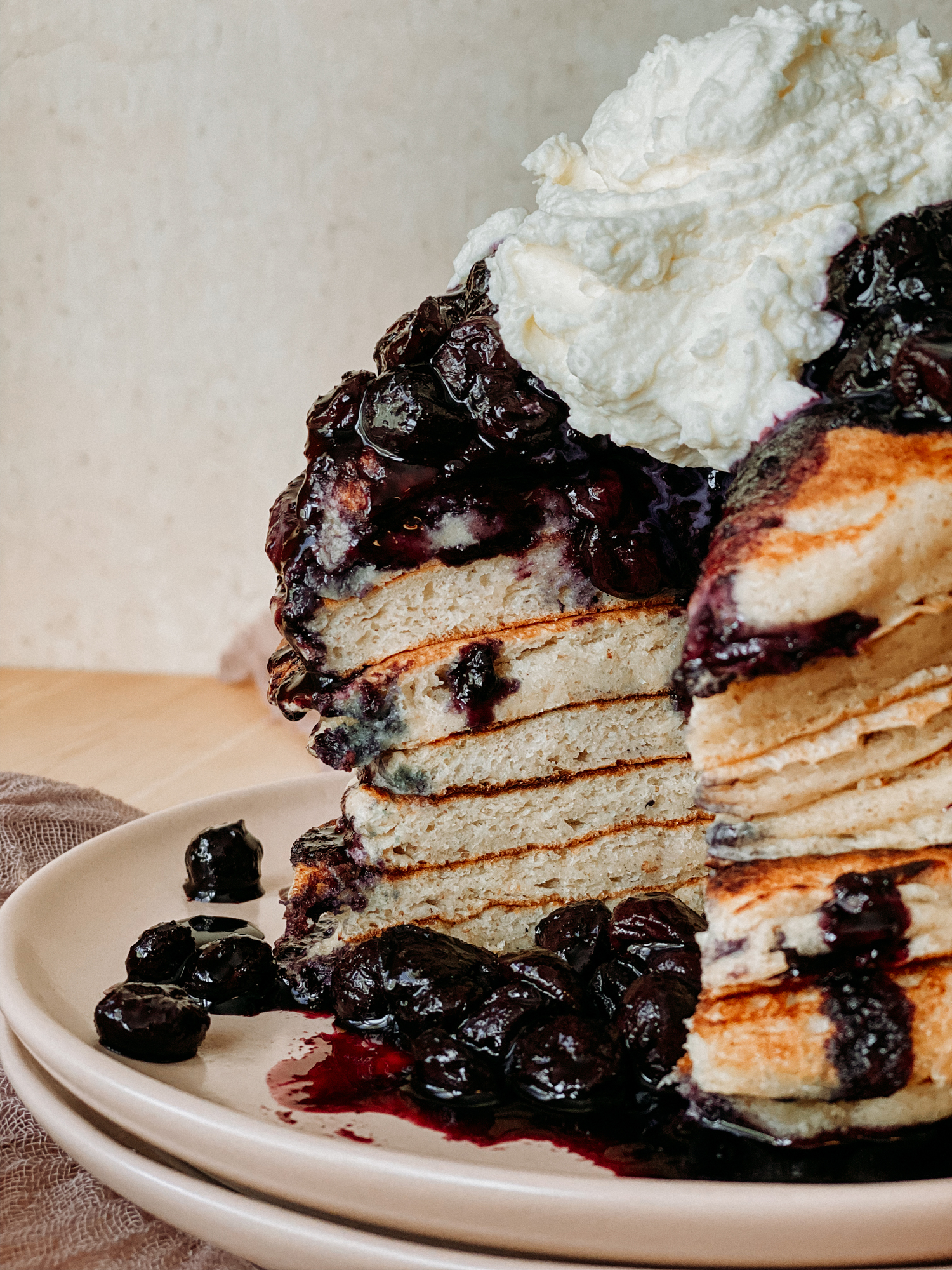 a stack of pancakes with blueberry sauce and whipped cream that have been sliced into so you can see the inside of the pancakes