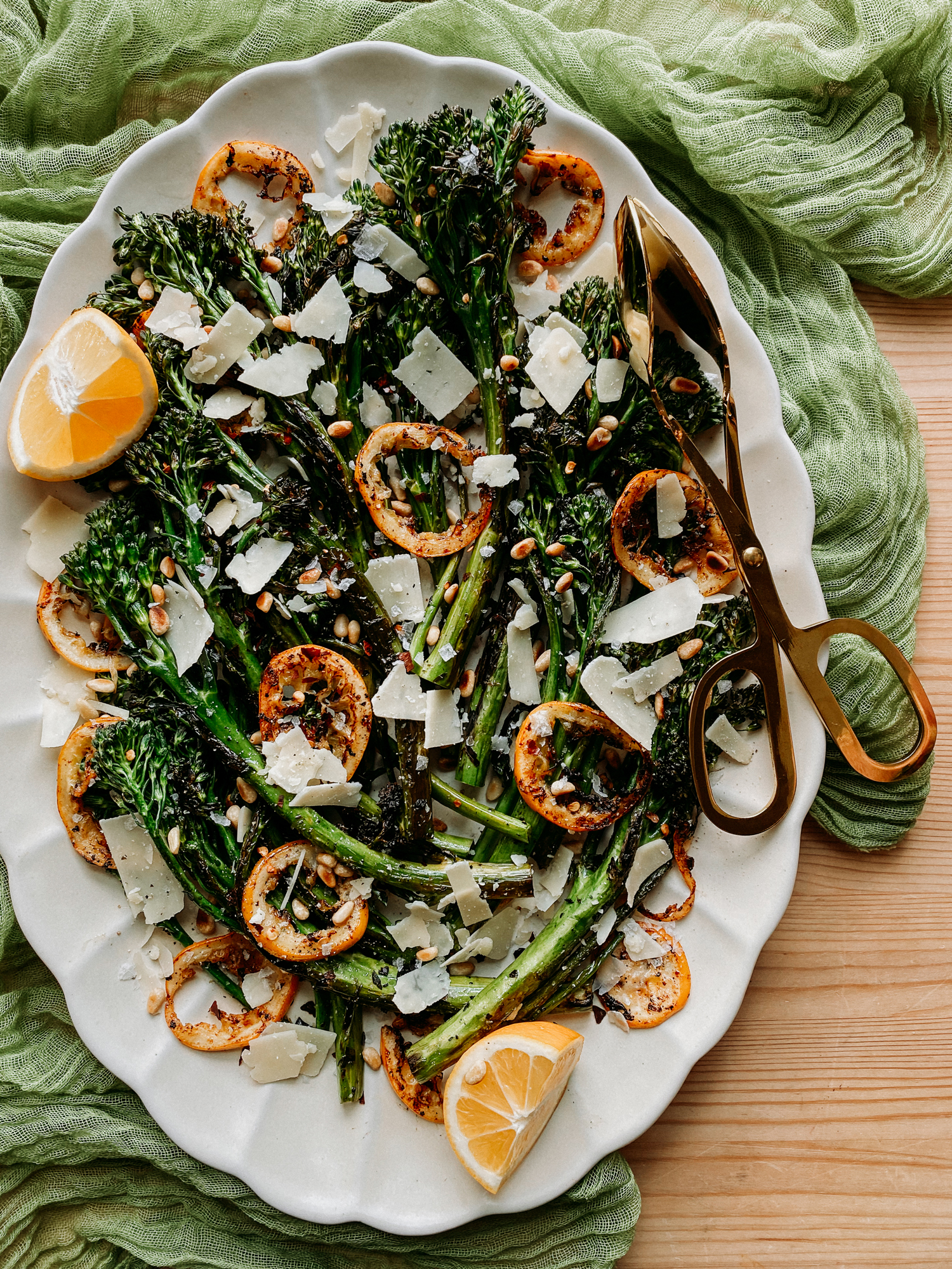 a platter with charred broccolini, browned lemon, pine nuts, and parmesan