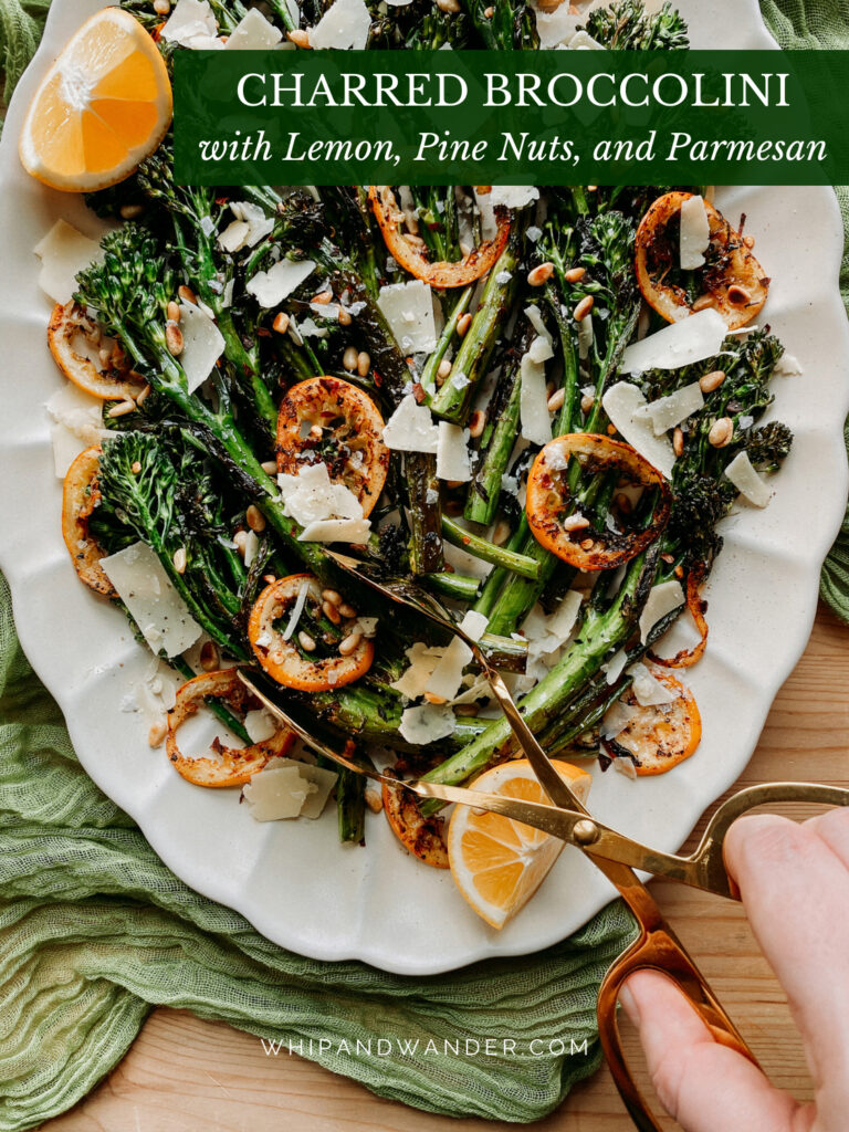 a hand dishing up broccolini with tongs from a white platter