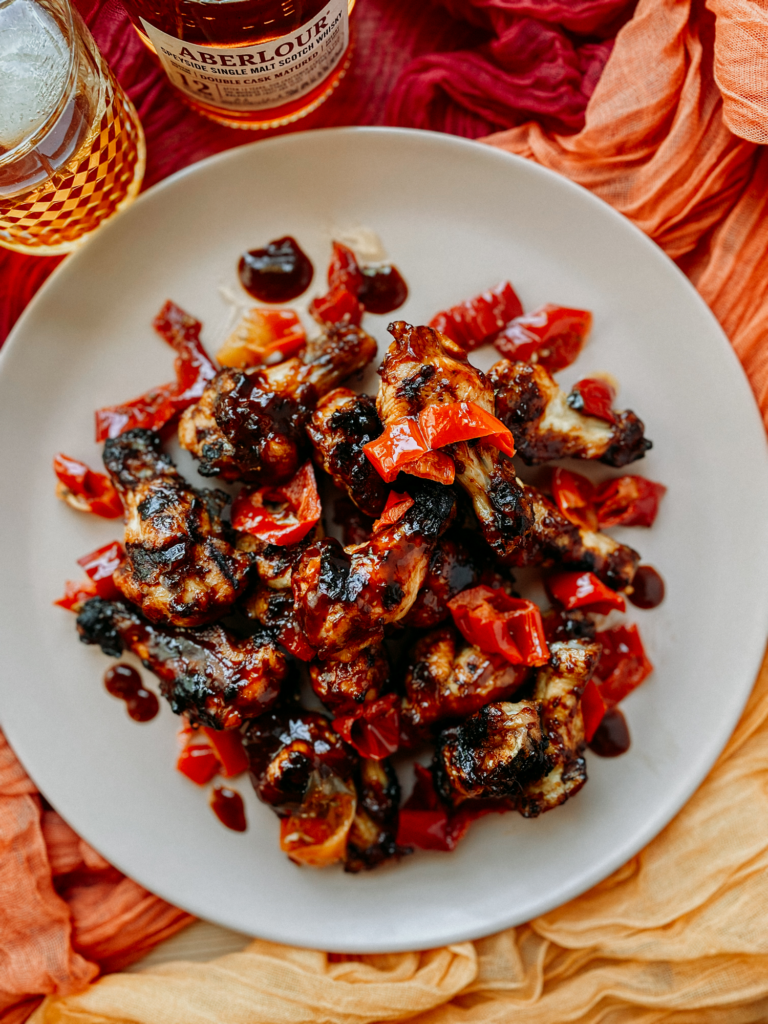 a plate of bbq chicken wings on a gauzy orange cloth