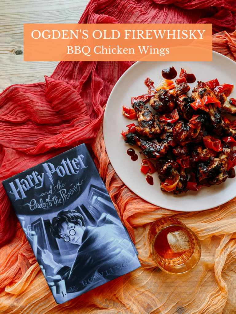 a plate of chicken wings with bbq sauce and peppers on a red and orange cloth with a harry potter book resting nearby