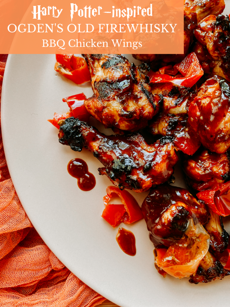 chicken wings that have bbq sauce and red peppers on top on a light pink dish