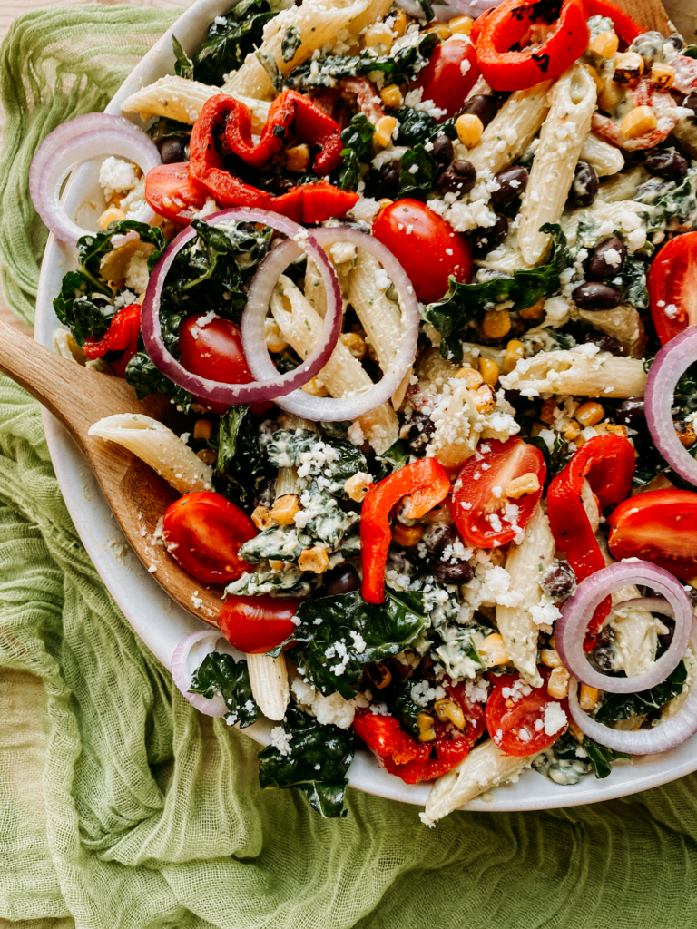 closeup of pasta salad with peppers and tomatoes and kale