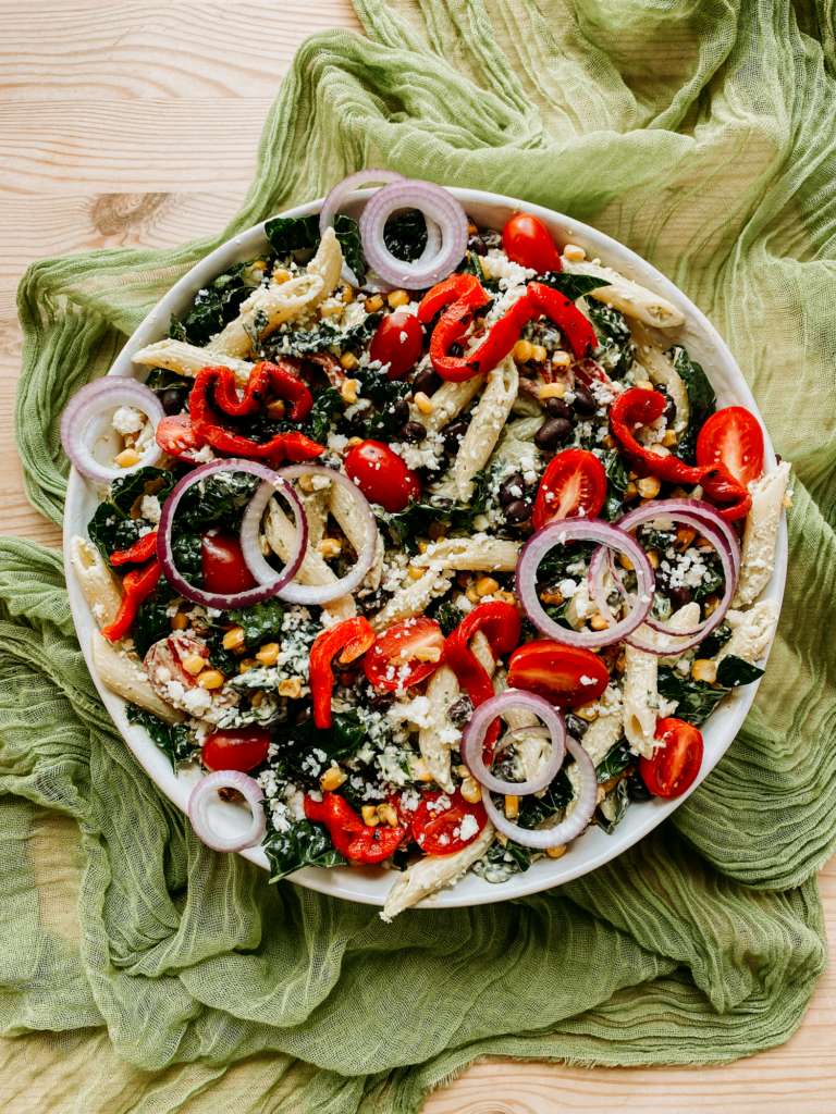 Southwest Pasta Salad in a large white bowl resting on a gauzy green cloth