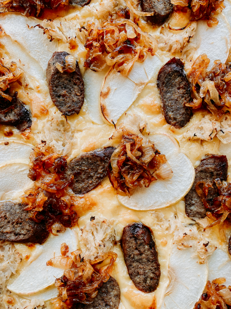 caramelized onions on top of a pizza with apples and bratwurst