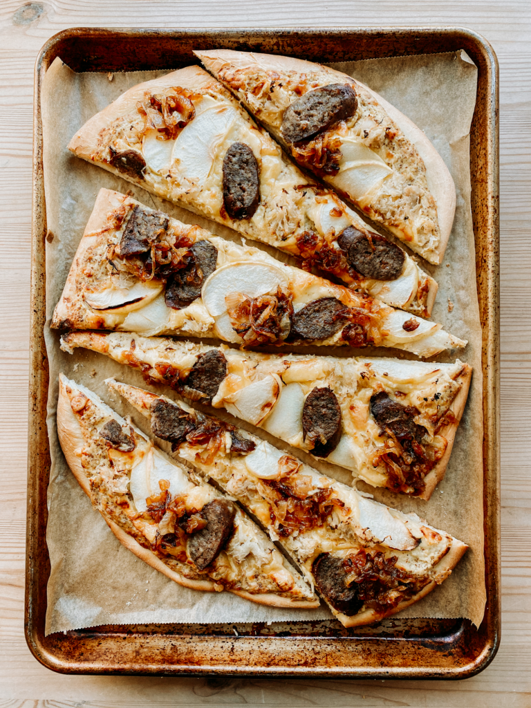 slices of oktoberest pizza with bratwurst on a baking sheet