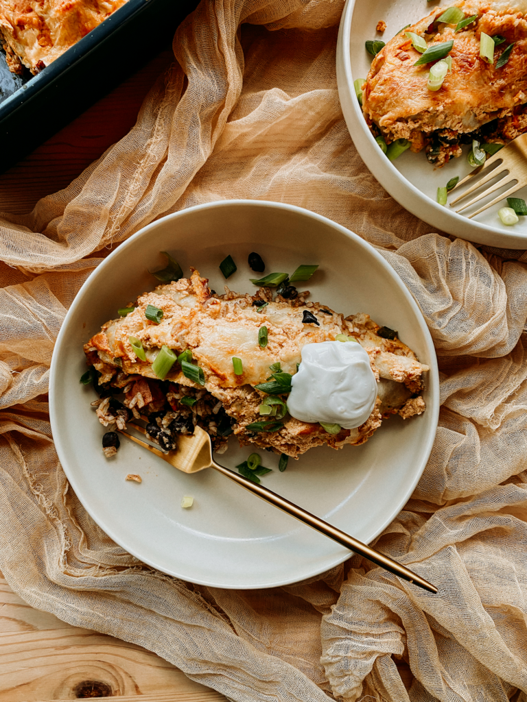 a gold fork resting in a bowl with a black bean and sweet potato enchilada