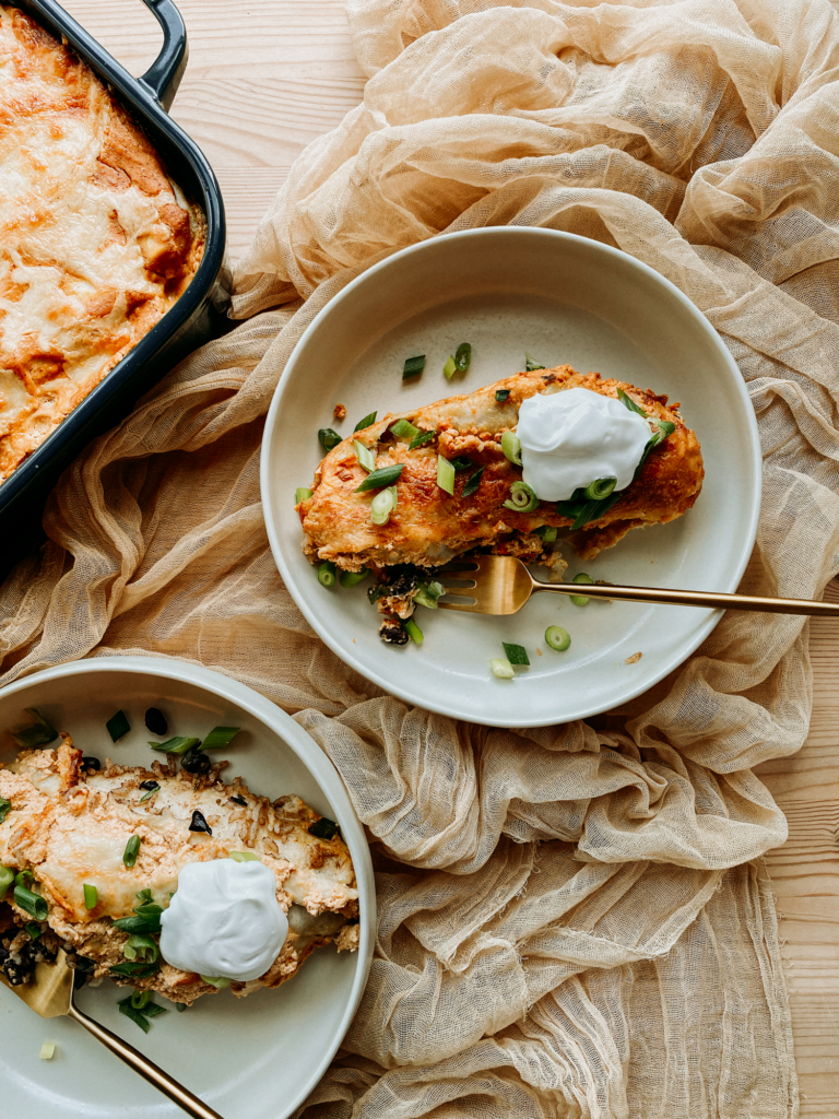two shallow bowls containing enchiladas on a tan cloth