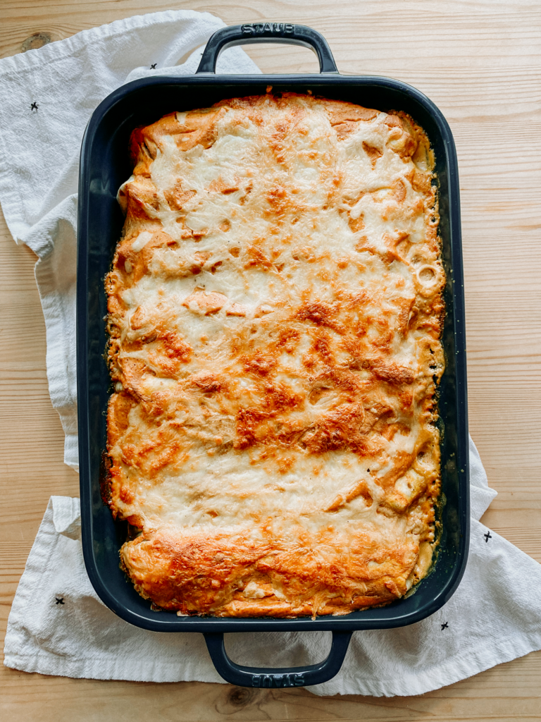 a pan of Sweet Potato and Black Bean Enchiladas with Chipotle Pumpkin Sauce resting on a white cloth on a wooden surface