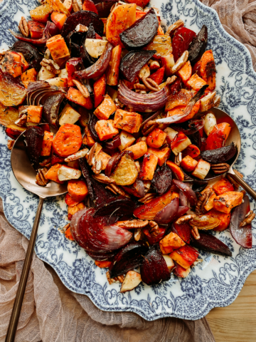 a brass serving spoon resting in a dish of roasted root vegetables