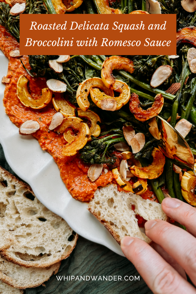 a hand using a piece of bread to wipe up romesco sauce from a platter of vegetables