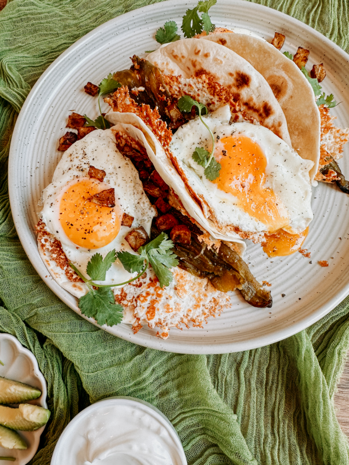 breakfast tacos on a white plate with cilantro and eggs