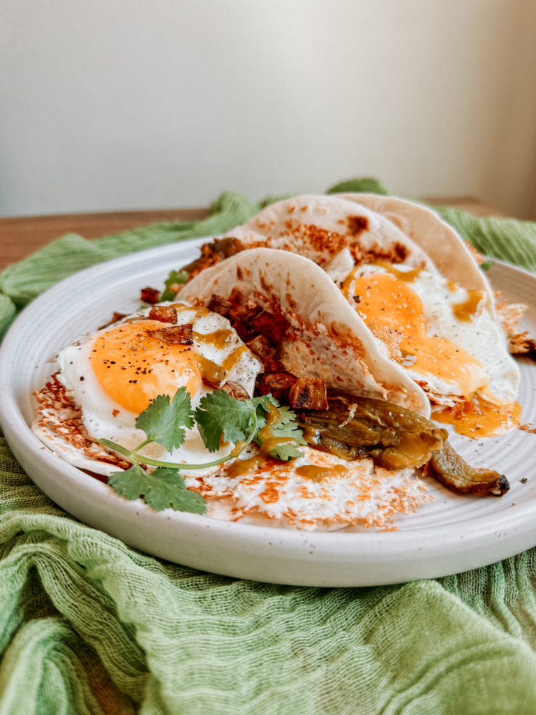 a plate of brunch tacos with eggs and green chilis