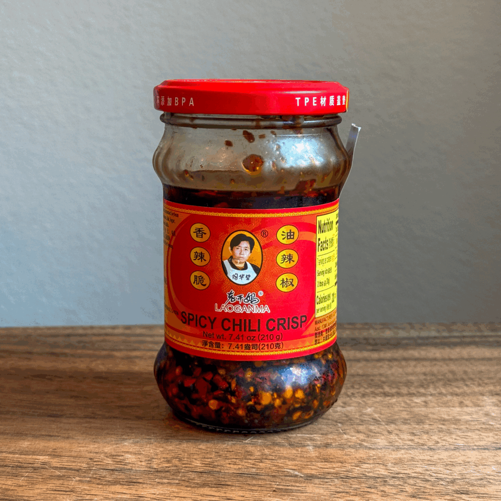 Jar of Lao Gan Ma Spicy Chili Crisp on a wooden table.