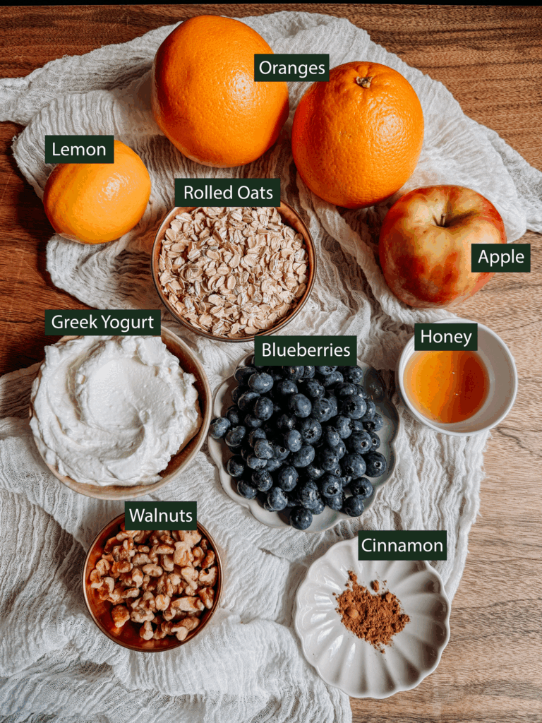 Ingredients for Princess Diana’s Overnight Oats including oranges, lemon, rolled oats, Greek yogurt, apple, blueberries, walnuts, honey, and cinnamon.