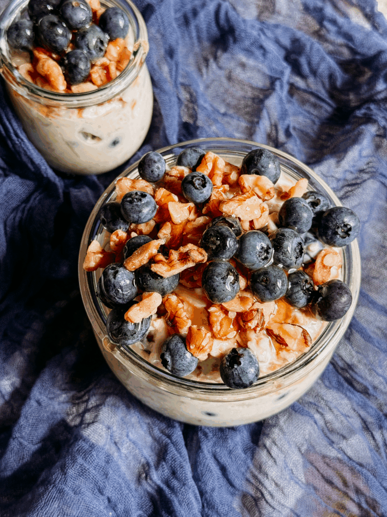 Close-up of overnight oats with fresh blueberries and toasted walnuts in glass jars.