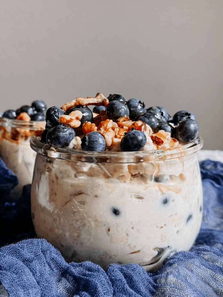 Glass jar filled with Princess Diana’s Overnight Oats topped with blueberries and walnuts.