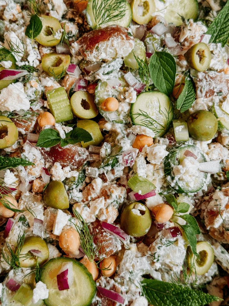 Close-up of tzatziki potato salad with cucumbers, olives, red onion, chickpeas, and feta.