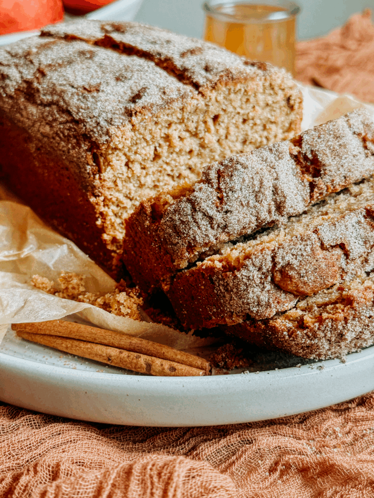 Close-up of sliced apple cider donut bread showing soft crumb and cinnamon-sugar crust.