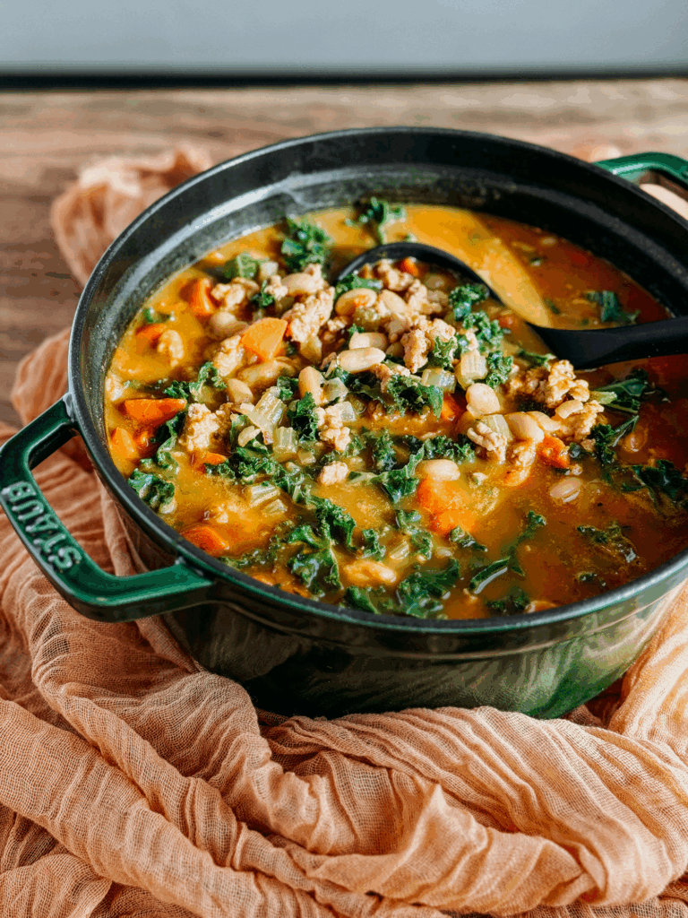Turkey Pumpkin White Bean Chili simmering in a green Dutch oven.