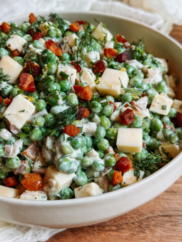 Herby pea salad with Gruyère and crispy pancetta in a white serving bowl