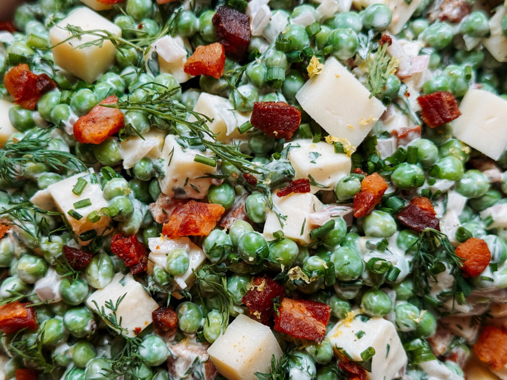 Close-up of herby pea salad with Gruyère, crispy pancetta, and fresh herbs
