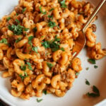 Close-up of creamy Instant Pot Hamburger Helper with elbow macaroni, ground beef, cheddar sauce, and parsley in a white bowl.